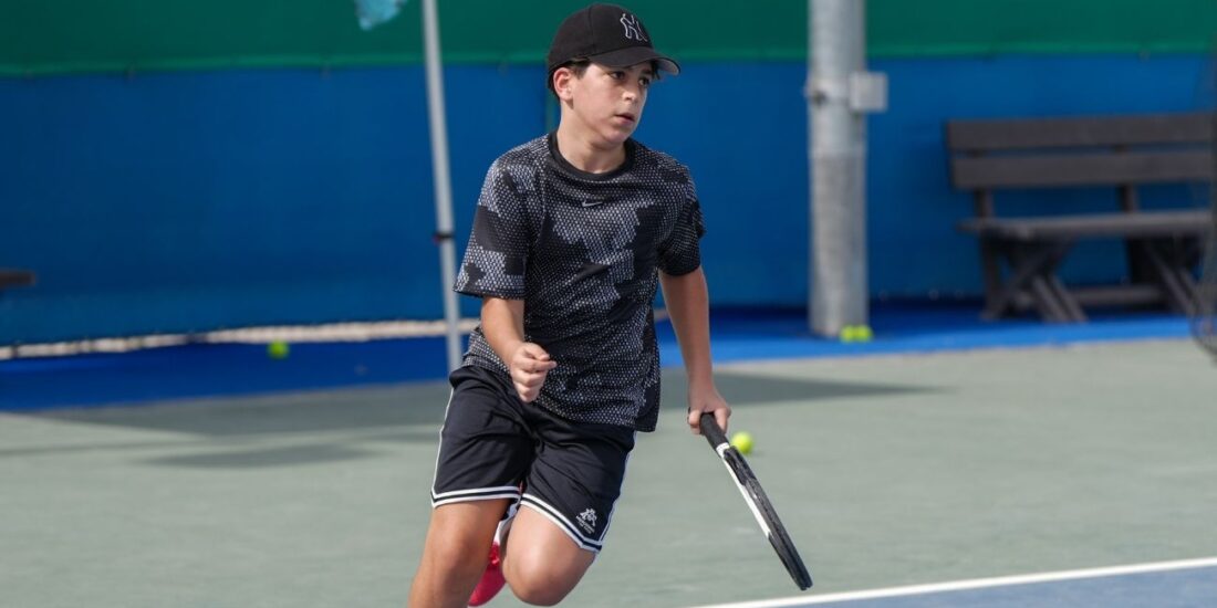 A boy learning tennis at a kid's tennis coaching in dubai sports city at ISD ProStyle Tennis