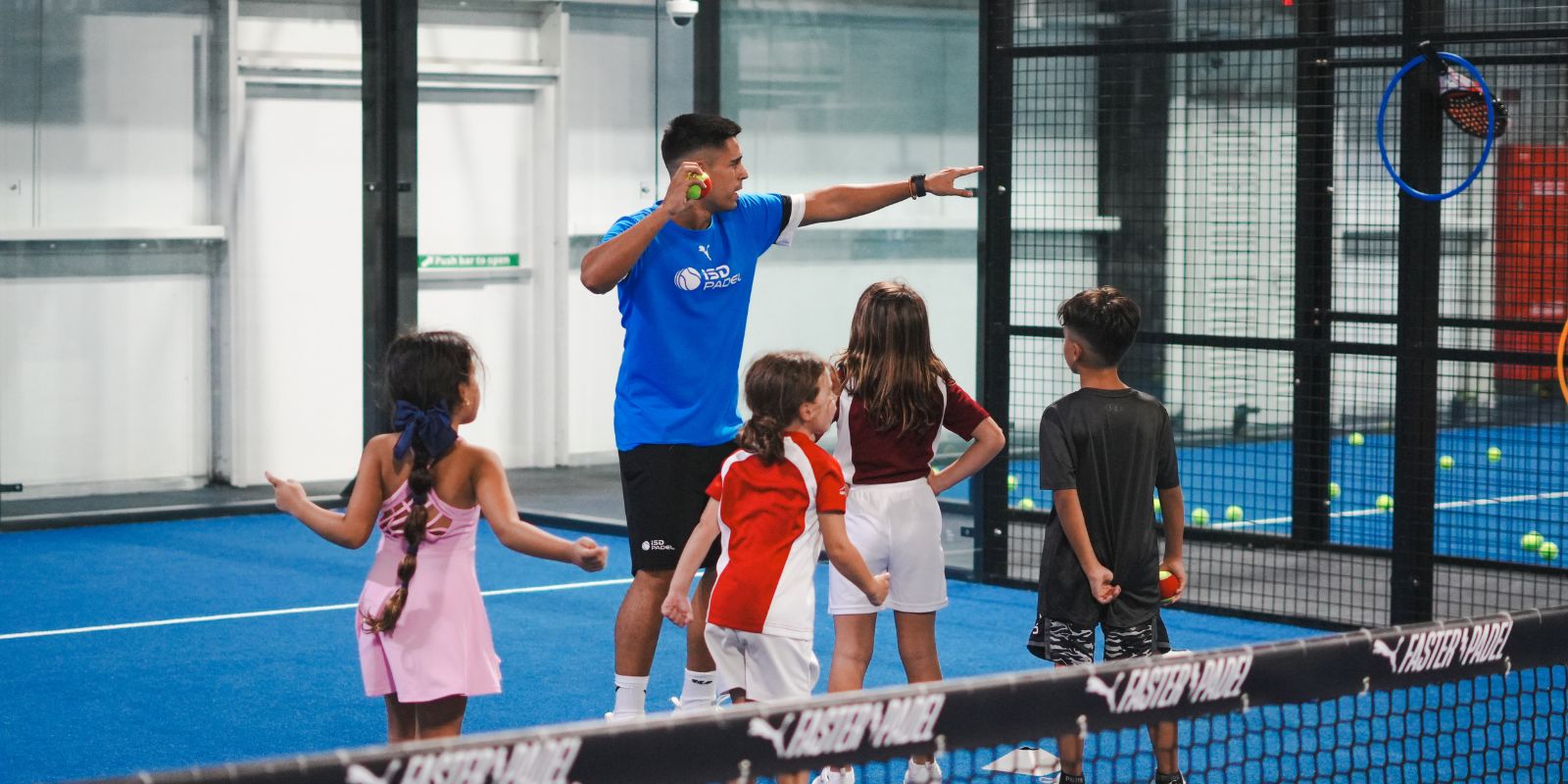 Padel coach Dani Casanova with a group of kids learning to play Padel at ISD Padel Academy