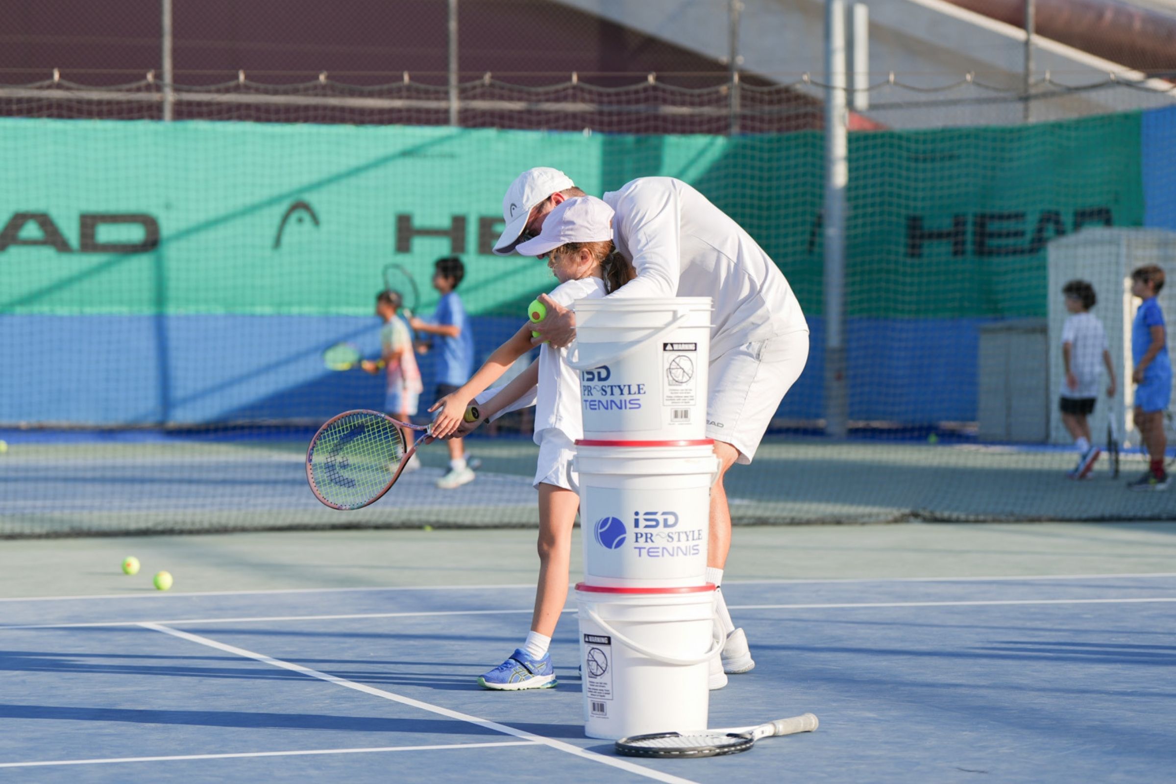 A Tennis coach during a session with a child at ISD ProStyle Tennis Academy in Dubai Sports City