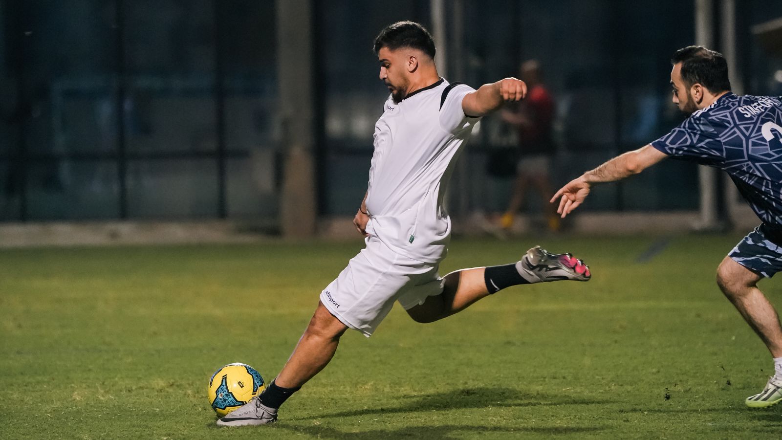 A corporate football player kicking a football during a match in the Dubai corporate football league