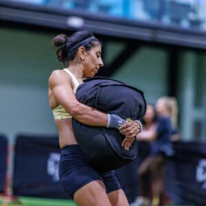 A woman carrying a sand bag in the middle of an event in the precision pairs competition held at ISD Dubai Sports City