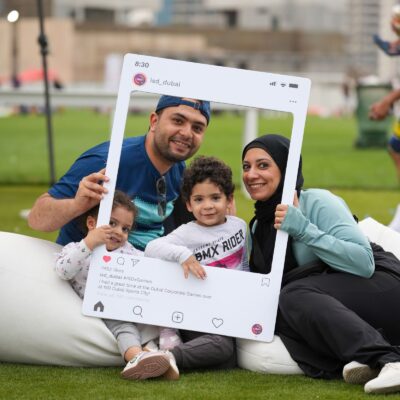 A family posing for a picture with the ISD Instagram Frame at the dubai corporate games 2025 in ISD Dubai Sports City
